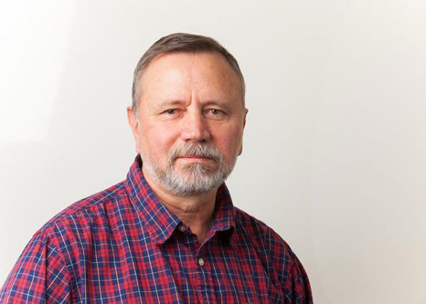 Portrait of a man in a plaid shirt in front of an off-white background