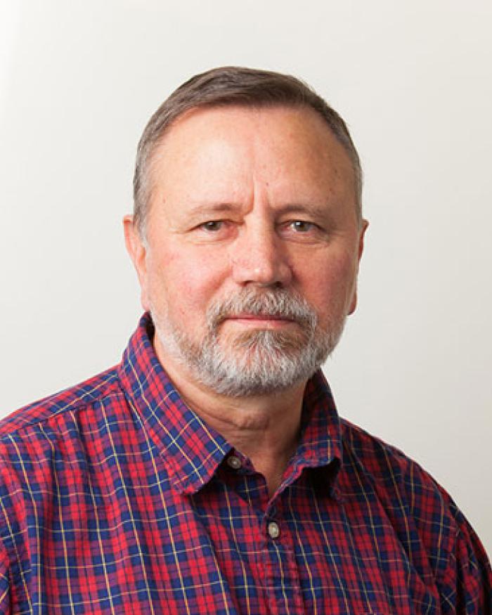 Portrait of a man in a plaid shirt in front of an off-white background